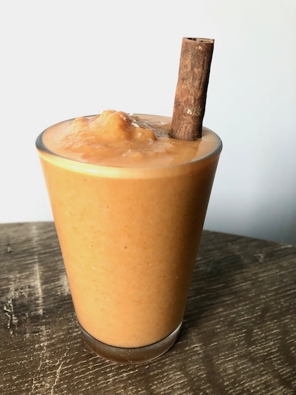 Coconut carrot apple smoothie with a cinnamon straw.