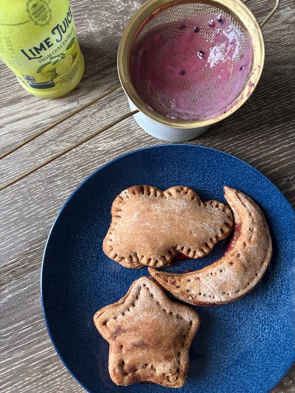 fruit pastry tart on a plate with blackberry glaze close by.