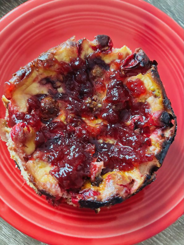 Basque-style sheep's cheesecake baked in lower oven temperatures with cranberries and cranberry sauce.