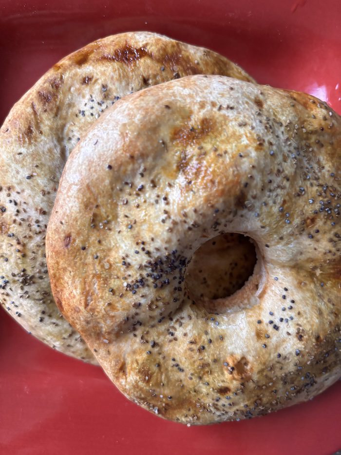 Sourdough bagel halves with matcha and poppy seeds.